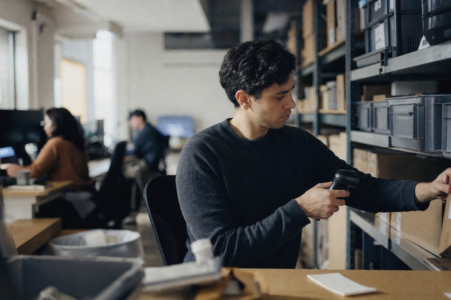 An inventory coordinator scans a box on a stock room shelf